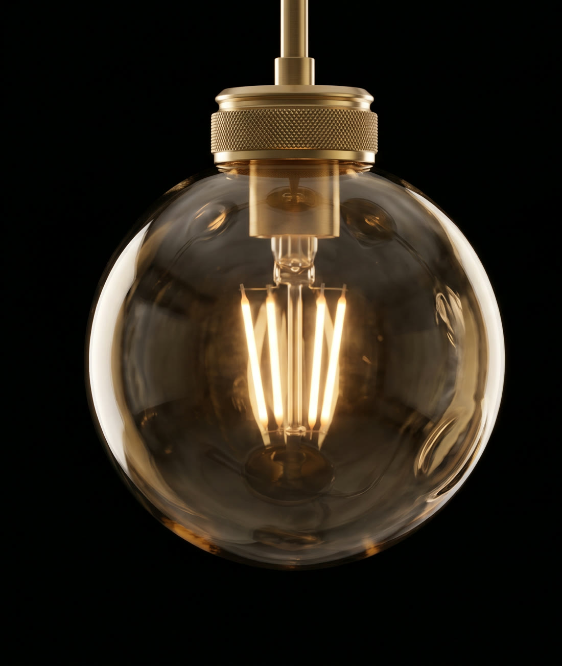 Extreme close-up of a hand-blown smoked-amber glass globe with a warm filament.